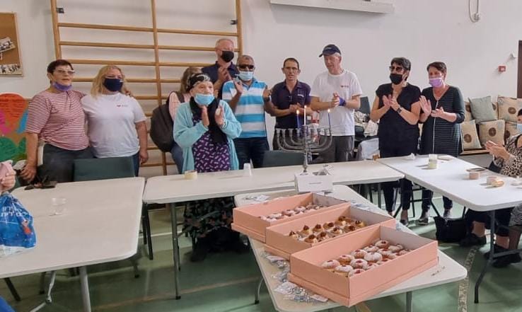 עובדי נטפים וחברי עמותת מגדל אור מדליקים נר חנוכה. קרדיט - יח"צ נטפים