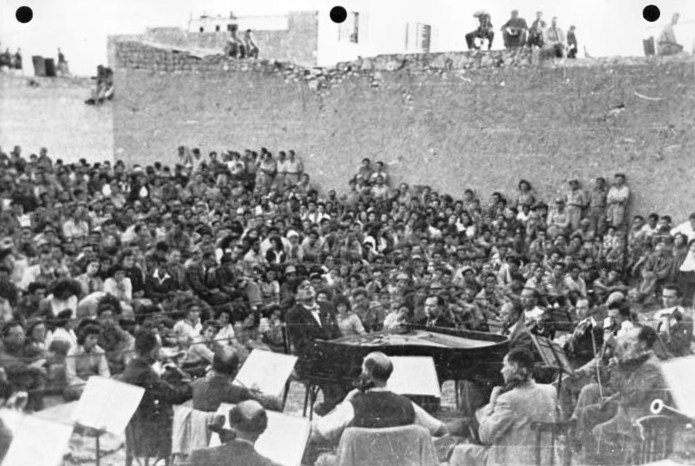 ליאונרד ברנשטיין מנגן עם התזמורת הפילהרמונית הישראלית בפני חיילים בקונצרט פתוח בבאר שבע לאחר שחרורה, 1948 (מתוך ויקיפדיה)